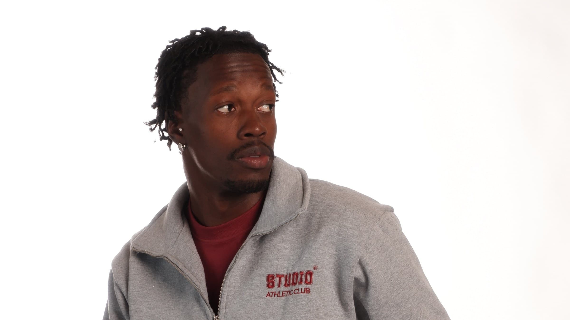 Homem de casaco Studio Fleece cinza mescla, com a inscrição collegiate Studio Athletic Club bordada em vermelho vinho no peito, sobre fundo branco de estúdio