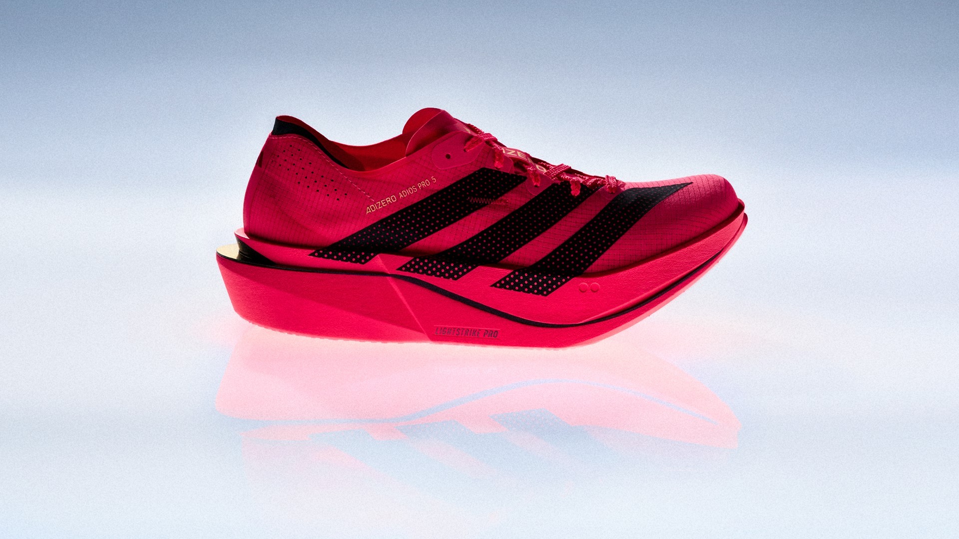 Perfil do adidas Adizero Adios Pro 5 vermelho em fundo claro, com o aro de carbono ENERGYRIM visível na lateral da entressola Lightstrike Pro