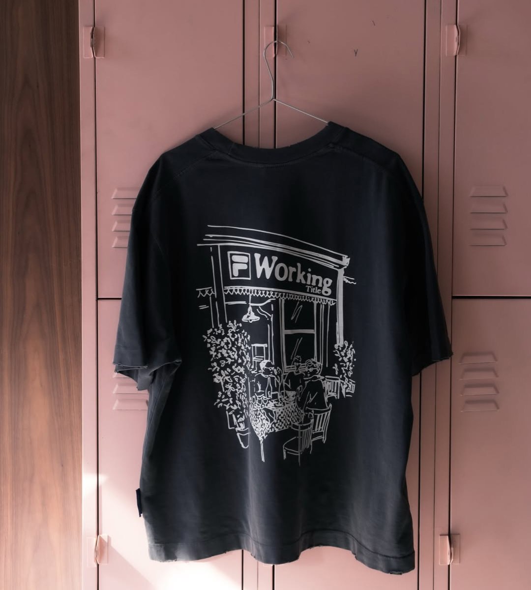 Camiseta preta com estampa em traço fino de uma fachada de trattoria italiana, pendurada em armários rosa