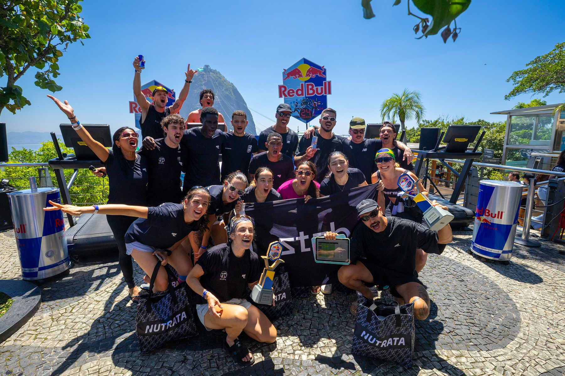 Integrantes da crew Stab comemoram com o troféu e a bandeira do grupo, diante das esteiras e do Pão de Açúcar