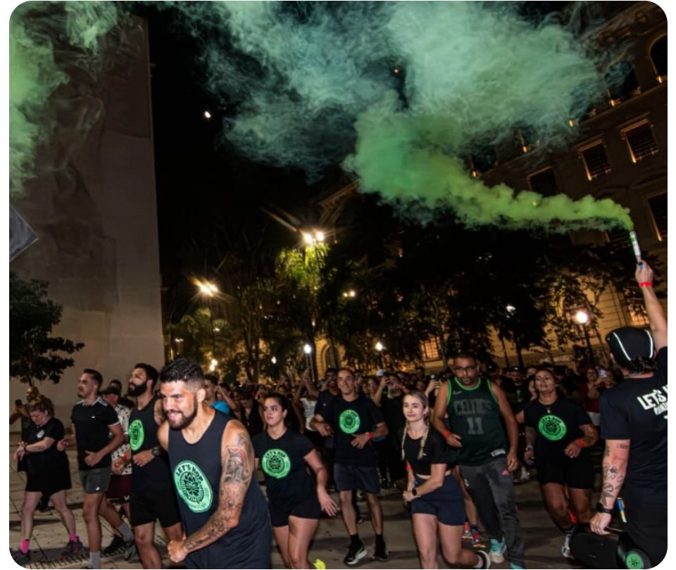 Corredores do Let's Hop atravessam a rua à noite com sinalizador de fumaça verde